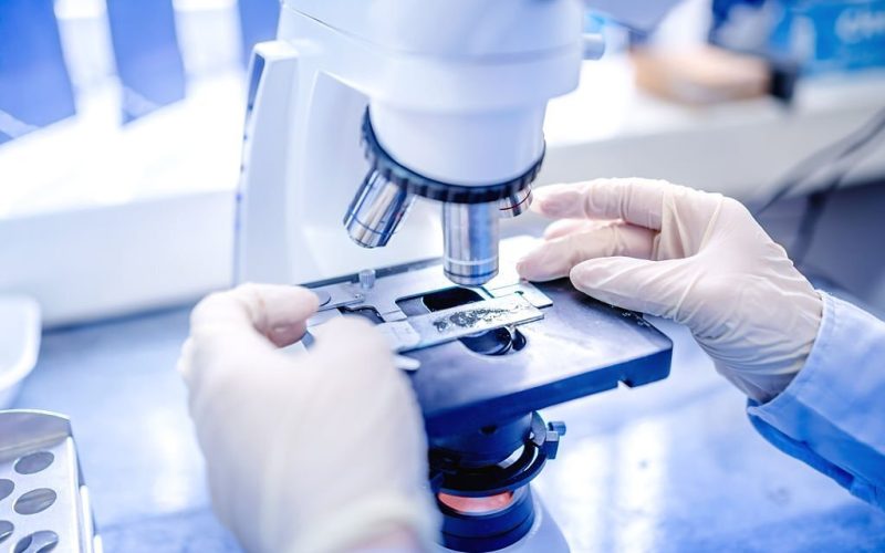 scientist hands with microscope, examining samples and liquid. Medical research with technical equipment